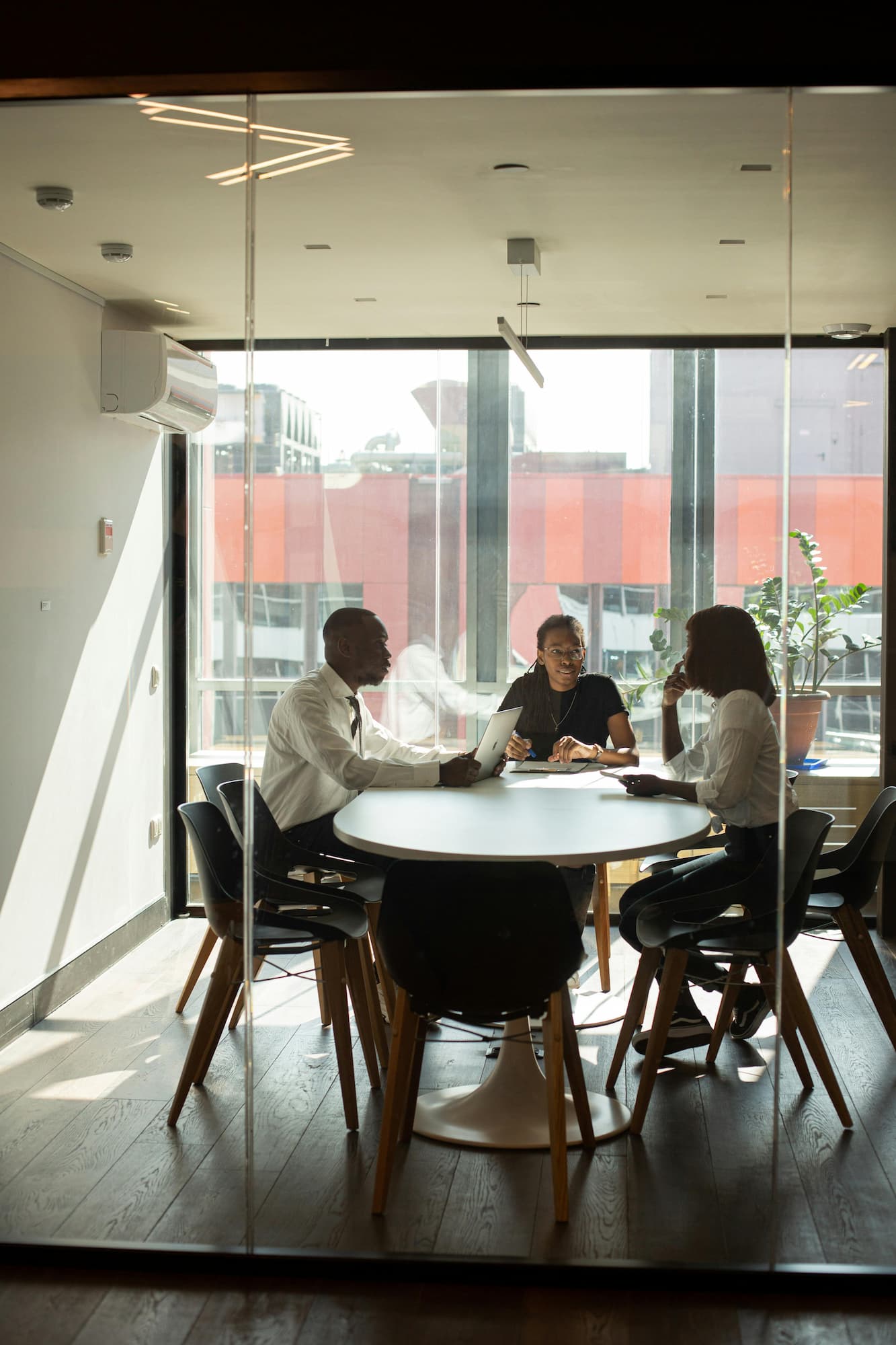 Three employees of a company seated around a table and discussing small business funding.